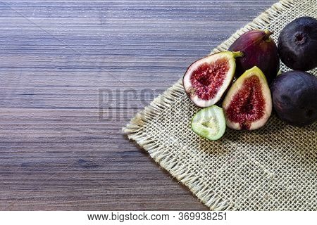 Figs, green leaves on rustic wooden background