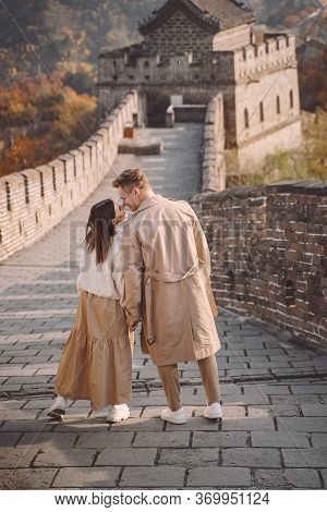 Beautiful Young Couple Holding Hands And Showing Affection At The Great Wall Of China.