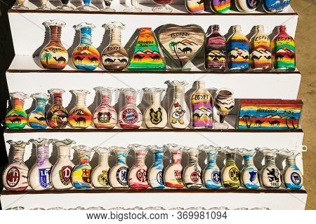 Hurghada, Egypt- Jan 27 , 2020:Decorative glass bottles with colored sand inside and shapes of desert and camels in street shop. Egupt.