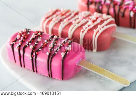 A Close Up Of Homemade Cakesicles For Valentines Day On A Marble Slab.