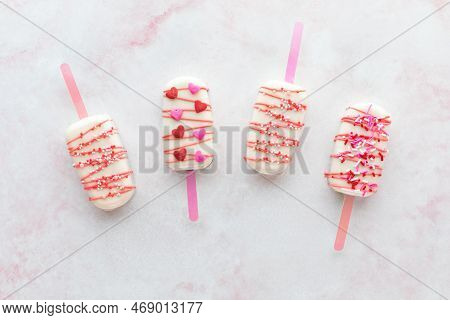 Homemade Decorated Cakesicles For Valentines Day, On A Pink Marble Surface.
