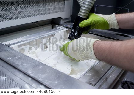 Male Worker Taking Out Models From White Polyamide Powder In Working Chamber Of 3d Printer, Cleaning