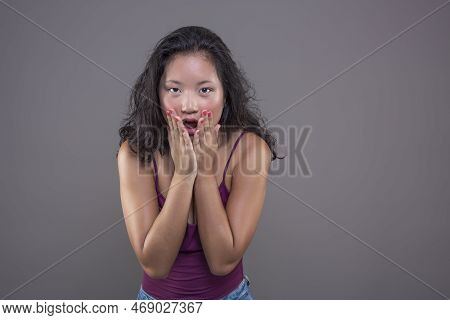 Young Asian Woman In Tank Top With Funny Expression Isolated From The Background