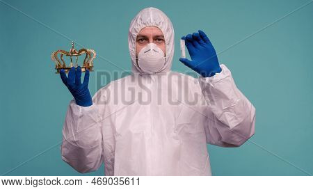 A Male Doctor In Protective Overalls And A Mask Holds An Ampoule With A Vaccine And Crown In His Han