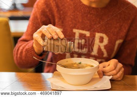 Woman Adds Black Pepper To Fish Soup With Salmon And Sea Bass Fish At Seafood Cafe Or Restaurant. Fe