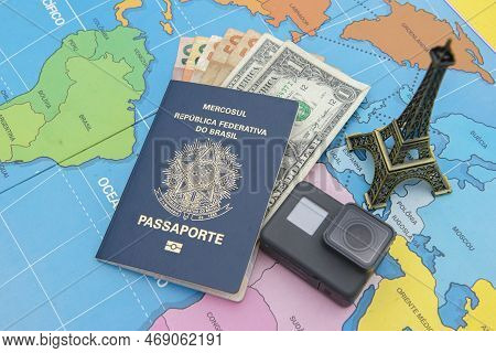 Bauru, Brazil - 11 Jan, 2023: Passport, With Several Banknotes Inside It, Camera And Miniature Of Th