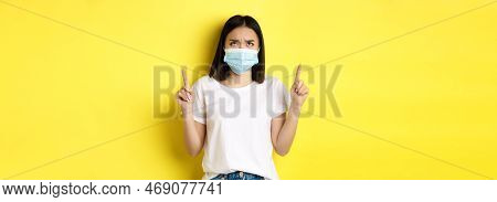 Covid-19, Pandemic And Social Distancing Concept. Disappointed Asian Girl In Medical Mask, Frowning 