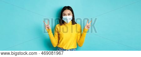 Covid-19, Social Distancing And Pandemic Concept. Kawaii Asian Woman Showing Peace Signs And Smiling