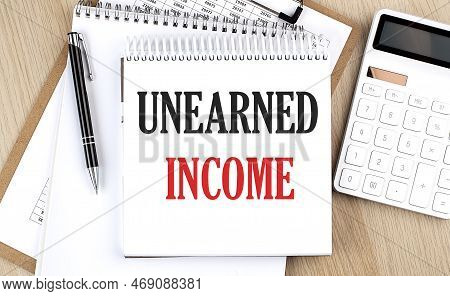 Unearned Income Is Written In White Notepad Near A Calculator, Clipboard And Pen. Business