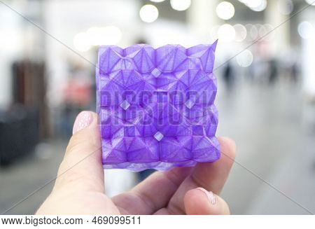 Person Holding A Abstract Model Printed On A 3d Printer From Purple Plastic On His Hand On A Blurred