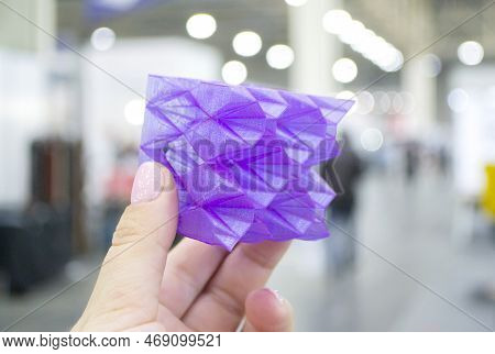 Person Holding A Abstract Model Printed On A 3d Printer From Purple Plastic On His Hand On A Blurred