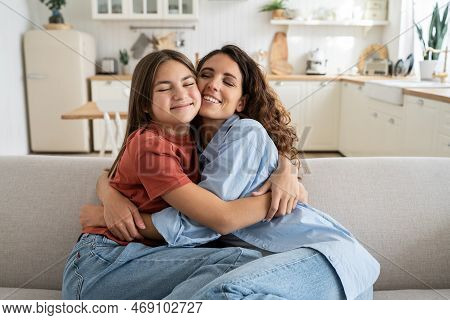 Happiness In Motherhood. Joyful Young Mother And Teen Daughter Cuddling Hugging While Sitting On Sof