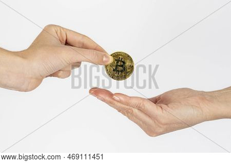 Woman's Hand Giving A Bitcoin Coin To Another Woman On White Background