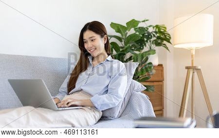 Woman using laptop to work or do homework at home with smiling face in her living room, Creating hap