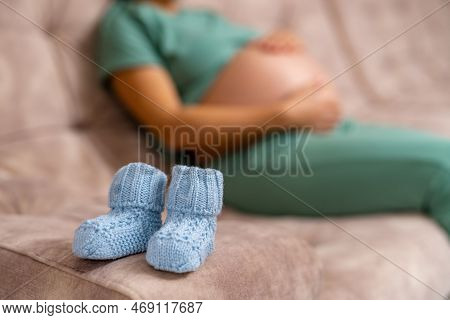 Happy Pregnant Lady Holding Small Shoes. Maternity Big Belly.