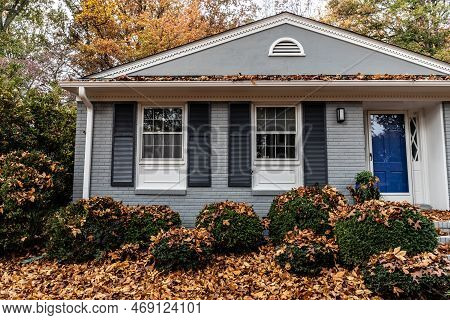 Portion Of An Old Brick Ranch Home With Roof, Bushes, And Yard In Need Of Leaf Removal Services, Fal