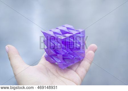 Person Holding A Abstract Model Printed On A 3d Printer From Purple Plastic On His Hand On Gray Back