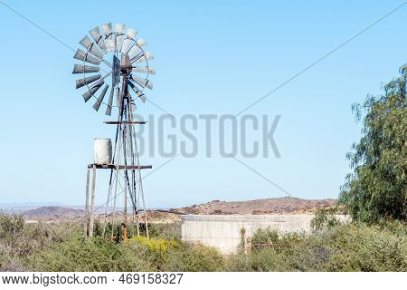 A Typical Karoo Landscape, With A Windmill, Water Tank And Dam, On Road R356 Between Loxton And Fras