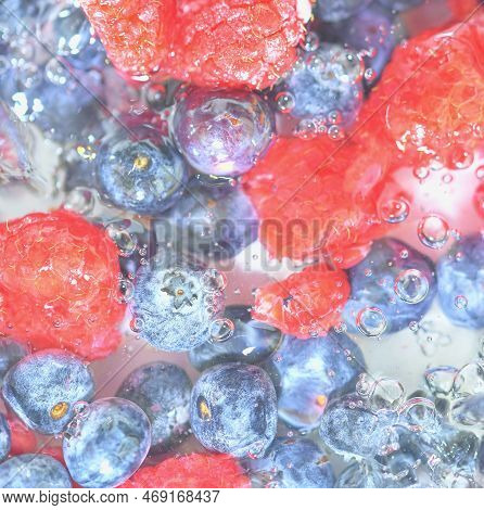 Water With Fresh Berries, Close-up. Close-up View Of The Blueberries And Raspberries In Water Backgr