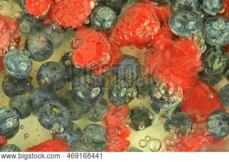 Water With Fresh Berries, Close-up. Close-up View Of The Blueberries And Raspberries In Water Backgr