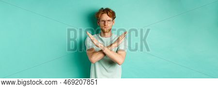 Serious And Confident Redhead Man In T-shirt And Glasses Saying No, Showing Cross Gesture To Stop Yo