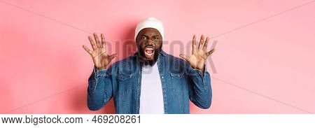 Angry African-american Guy In Beanie, Scare You, Roaring And Screaming, Showing Hands, Standing Ove 