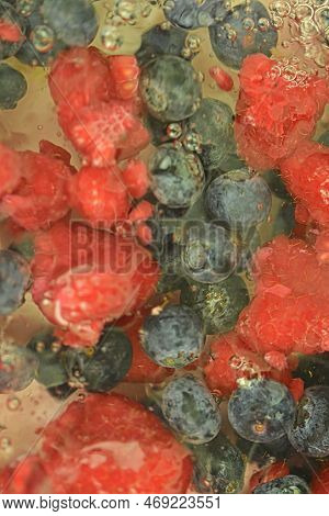 Water With Fresh Berries, Close-up. Close-up View Of The Blueberries And Raspberries In Water Backgr