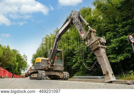Excavator With Hydraulic Jack Hammer  Breaking Asphalt In Preparation For Drainage Works Close Up An