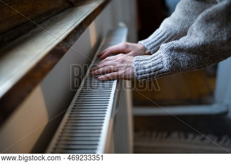 Closeup Of Woman In Woolen Sweater Wants To Keep Warmth In Apartment. Lady Puts Hands On Room Centra