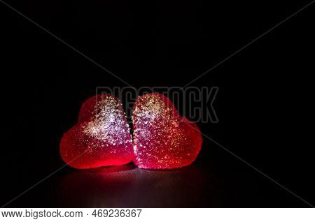 Two Red Sugar Marmalade Candies In Shape Of A Heart On A Black Background, Lit From The Side, With C