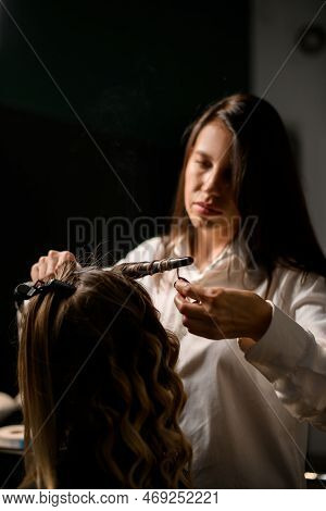 Professional Hairdresser Stylist Curls Long Female Hair With Curling Iron And Makes Styling