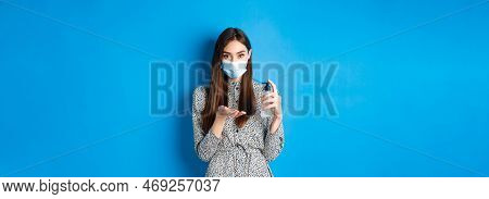Covid-19, Social Distancing And Healthcare Concept. Beautiful Girl In Medical Mask Using Hand Sanizi