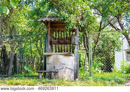 Old Well With Iron Bucket On Long Forged Chain For Clean Drinking Water