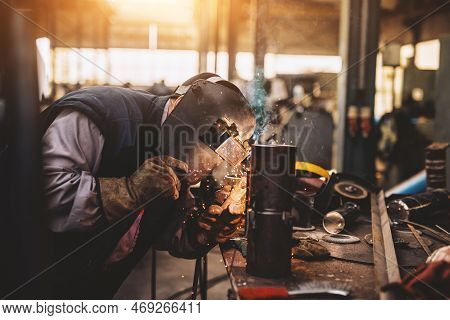 Profesional Welder In Protective Uniform And Mask Welding Metal Pipe On The Industrial Table With Ot