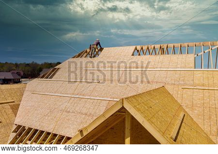An Unfinished House Is Being Reroofed By Roofer Who Is Working On Installation Of Plywood Roof