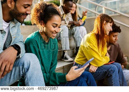 Young Group Of Diverse Student Friends Using Mobile Phone Outdoor. Millennial Generation People Havi