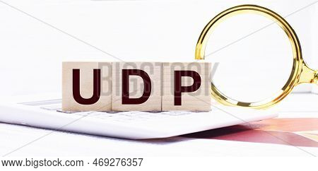 Three Wooden Cubes With The Text Udp User Datagram Protocol Stand On A White Calculator Near A Magni