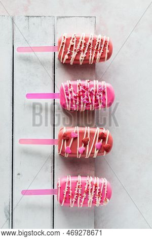 Homemade Decorated Cakesicles For Valentines Day On A Rustic Wooden Board.