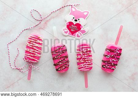 Homemade Decorated Valentine Cakesicles With A Valentine Card Attached To One.