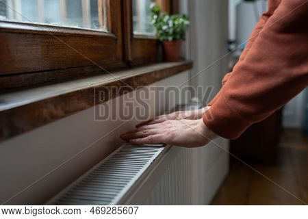 Closeup Of Man In Sweater Wants To Keep Warmth In Apartment. Female Puts Hands On Room Central Heati