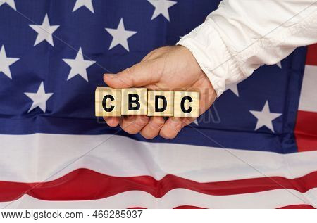 Business Concept. Against The Background Of The Usa Flag, A Man's Hand With Cubes With The Text - Cb