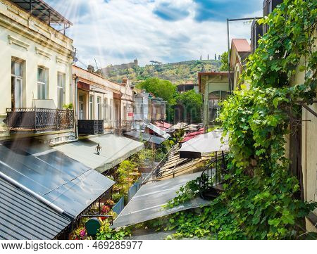 Street In Tbilisi Old Town With Restaurants, Balconies And Roofs. View From Above To Narikala Fortre