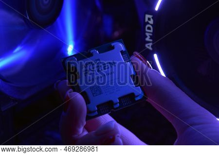 Close-up Of An Amd Ryzen 9 3900X Processor, Against The Backdrop Of Coolers With Light.