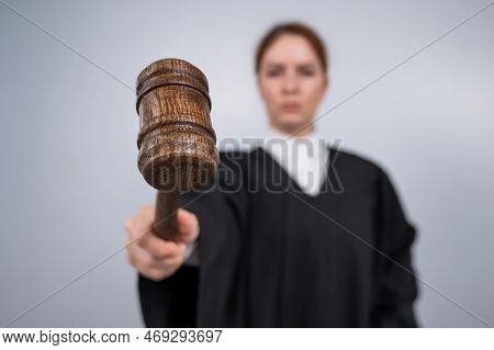 Steadfast Female Judge In A Robe Holding A Court Gavel.