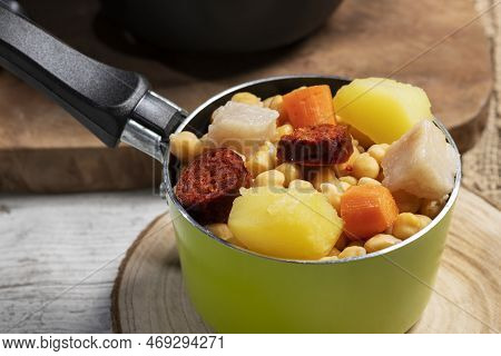 Cooked (cocido, Guiso) Stew, Chickpeas With Chorizo, Bacon, Carrot And Potato In Green Saucepan On W