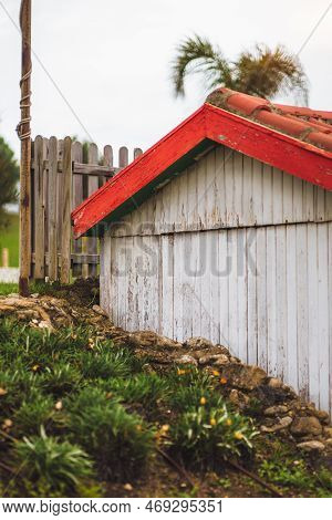 Vertical View Of Modest Wooden House Painted In White With Orange-red Tiles In An A Shape Situated O