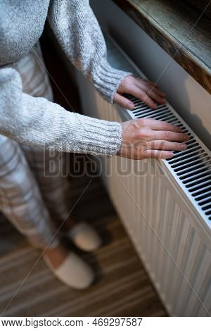 Closeup Of Woman In Woolen Sweater Wants To Keep Warmth In Apartment. Female Puts Hands On Room Cent