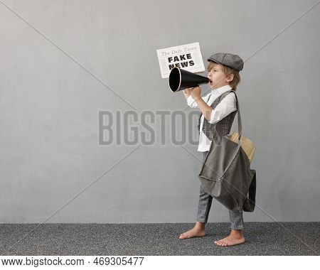 Newsboy Shouting Against Grunge Wall Background. Boy Selling Fake News