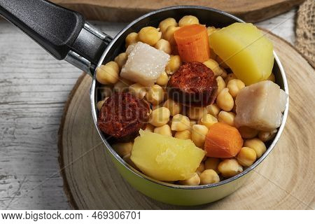 Cooked (cocido, Guiso) Stew, Chickpeas With Chorizo, Bacon, Carrot And Potato In A Green Saucepan An