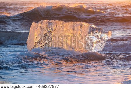 Diamond Beach In Iceland. Icebergs Shining On Black Volcanic Sand At Sunset. Clear Ice Crashed By Oc